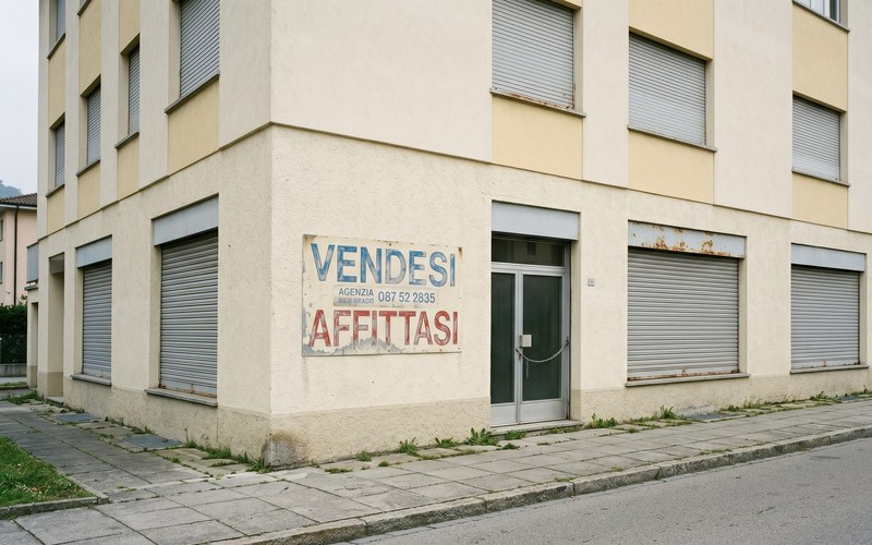 TicinoNews — Lugano e il valore strategico degli edifici dismessi: dalla vendita alla rendita pubblica · Leerstehendes Tessiner Gewerbegebäude mit den Aufschriften 'Vendesi · Affittasi'